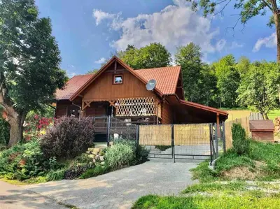 a large wooden house with a fence in front of it at Urokliwy drewniany dom z widokiem na Tatry in Tokarnia