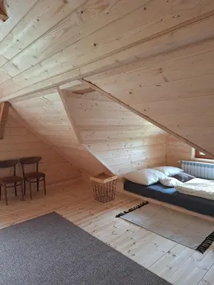 a room with a bed and a table in a attic at Urokliwy drewniany dom z widokiem na Tatry in Tokarnia
