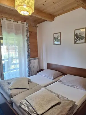 two beds sitting in a room with a window at Urokliwy drewniany dom z widokiem na Tatry in Tokarnia