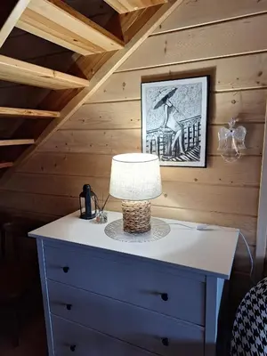 a table with a lamp on top of a dresser at Urokliwy drewniany dom z widokiem na Tatry in Tokarnia