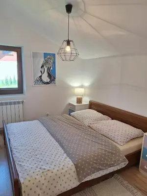 a bedroom with a bed and a pendant light at Urokliwy drewniany dom z widokiem na Tatry in Tokarnia