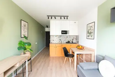 a kitchen and a living room with a table and a couch at Apartamenty Meiera in Kraków
