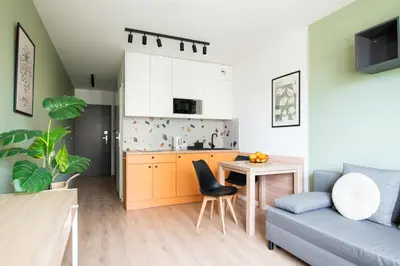 a kitchen and a living room with a couch and a table at Apartamenty Meiera in Kraków