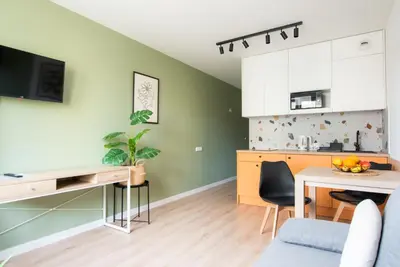 a kitchen and dining room with green walls and a table at Apartamenty Meiera in Kraków