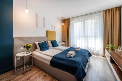 a bedroom with a bed with blue sheets and a window at Happy House Apartamenty in Kraków
