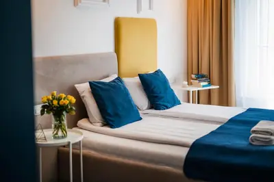 a bedroom with a bed with blue pillows and a vase of flowers at Happy House Apartamenty in Kraków