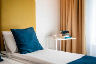 a bed with a blue pillow next to a window at Happy House Apartamenty in Kraków