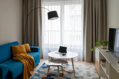 a living room with a blue couch and a table with a laptop at Happy House Apartamenty in Kraków
