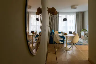 a mirror in a living room with a table and chairs at Happy House Apartamenty in Kraków