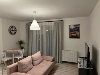 a living room with a pink couch and a table at Apartament Zlota Jesień 2C in Kraków