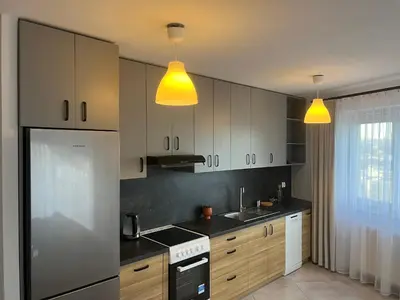 a kitchen with white cabinets and yellow lights at Apartament Zlota Jesień 2C in Kraków
