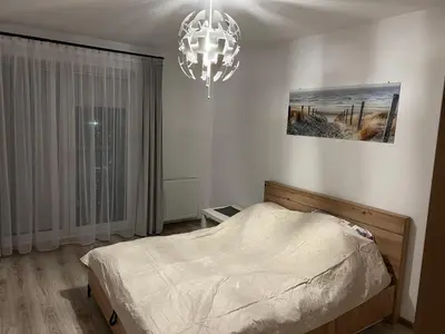 a bedroom with a bed and a chandelier at Apartament Zlota Jesień 2C in Kraków
