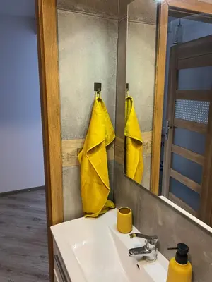 a bathroom with a sink with a mirror and yellow towels at Apartament Zlota Jesień 2C in Kraków