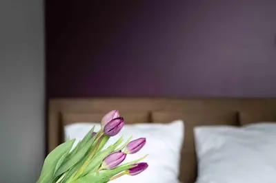 a bouquet of purple flowers sitting on top of a bed at 4Wings Apartments in Kraków