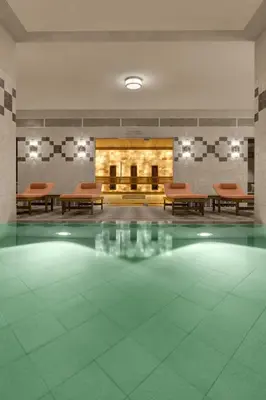 a large room with a fireplace and tables and a pool at Stradom House, Autograph Collection in Kraków