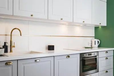 a kitchen with white cabinets and a sink at Verdant Oasis - Old Town Studio - by Upstairs in Kraków