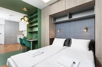 a bedroom with two beds and a kitchen in the background at Verdant Oasis - Old Town Studio - by Upstairs in Kraków