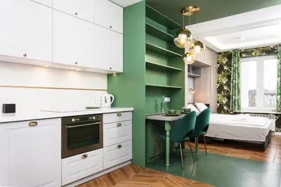 a kitchen with white cabinets and a green wall at Verdant Oasis - Old Town Studio - by Upstairs in Kraków