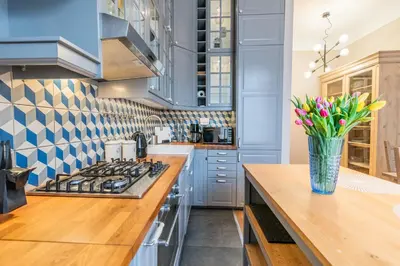 a blue kitchen with a vase of flowers on a table at Opera Apartments in Kraków