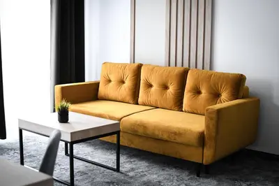 a yellow couch in a living room with a table at Pensjonat Zdrojowy Apartamenty in Rabka