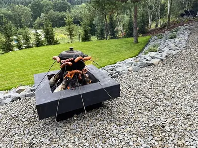 a person cooking food on top of a fire pit at Mucharskie Stodoły Stodoła I - Garden Spa in Jaszczurowa
