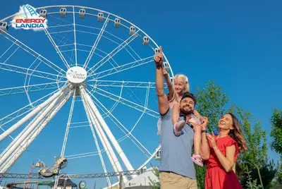a family standing in front of a ferris wheel at ApartPark Centrum Zator Bronze in Zator