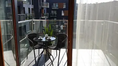 a small table and chairs on a balcony with glass walls at White Pearl Apartment in Kraków