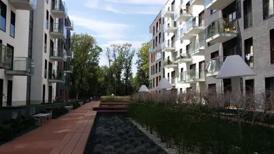 a path between two tall buildings with benches in front at White Pearl Apartment in Kraków