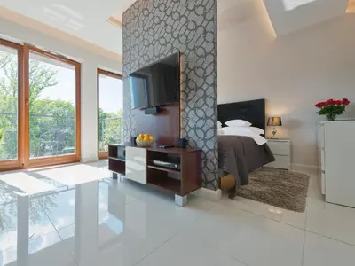 a bedroom with a bed and a tv on a wall at atHome in Kraków