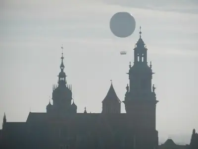 a hot air balloon flies over the buildings of a city at atHome in Kraków