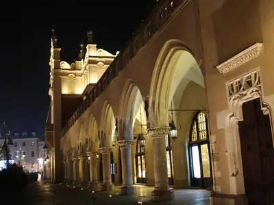 a building with arches and a clock tower at night at atHome in Kraków