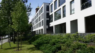 a building on a street with trees and bushes at Black Pearl Apartment in Kraków