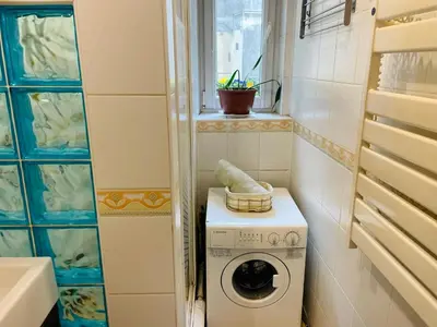 a small bathroom with a washing machine and a window at Sebastiana Studio Old Town in Kraków