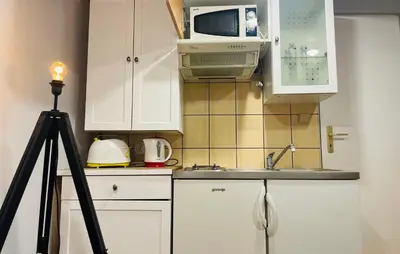 a kitchen with white cabinets and a microwave and a sink at Sebastiana Studio Old Town in Kraków