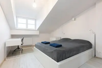 a white bedroom with a bed and a desk at Apartment Kazimierz near Wawel Castle in Kraków