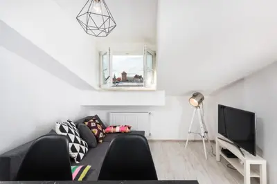 a living room with a black couch and a television at Apartment Kazimierz near Wawel Castle in Kraków