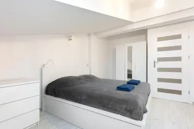 a white bedroom with a bed with blue sheets at Apartment Kazimierz near Wawel Castle in Kraków
