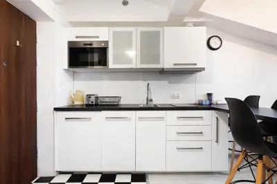 a kitchen with white cabinets and black counter tops at Apartment Kazimierz near Wawel Castle in Kraków