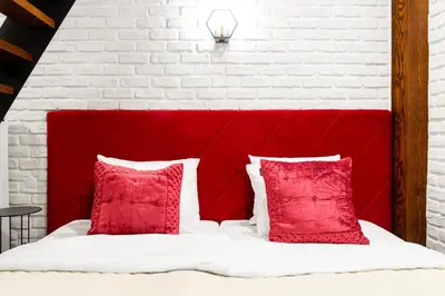 a bedroom with a red headboard and red pillows at Househost Apartment:Bracka 3/15A in Kraków