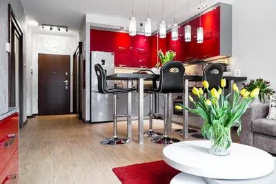 a kitchen with red cabinets and a table with black chairs at HOUSEHOST Apartment:Lubicz 17D/5 in Kraków