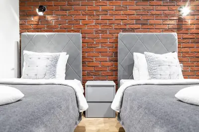 two beds in a room with a brick wall at HOUSEHOST Apartment:Bracka 3/15B in Kraków