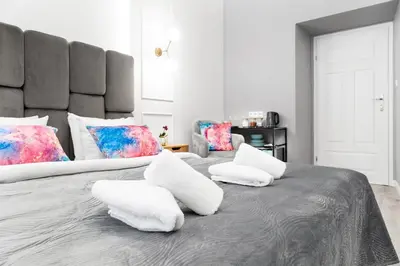 two beds with white pillows on a gray blanket at HOUSEHOST Apartment: Św.Gertrudy 10/0.2 in Kraków