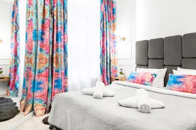 two beds in a bedroom with colorful curtains at HOUSEHOST Apartment: Św.Gertrudy 10/0.2 in Kraków