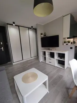 a living room with a white table and a tv at Przytulne mieszkanko in Oświęcim