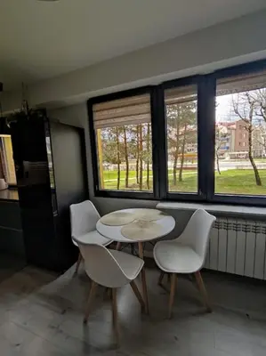 a table and chairs in a room with windows at Przytulne mieszkanko in Oświęcim