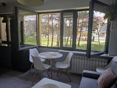 a room with a table and chairs and windows at Przytulne mieszkanko in Oświęcim