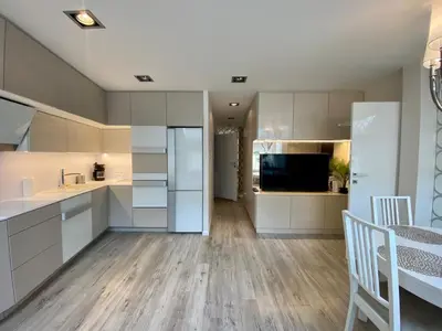 a kitchen with white cabinets and a dining room at Garbarska LUX with Air Condition in Kraków