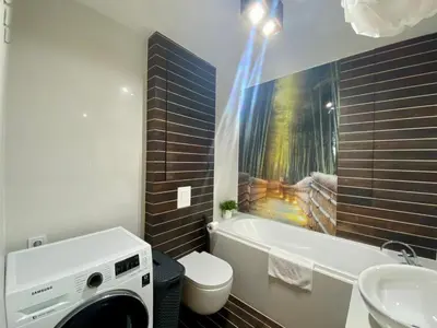 a bathroom with a washing machine next to a bath tub at Garbarska LUX with Air Condition in Kraków