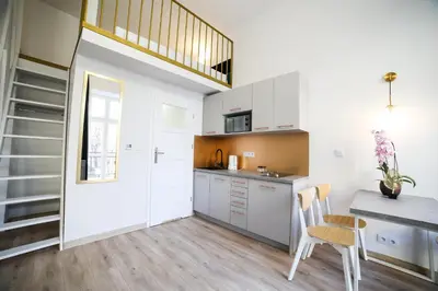 a kitchen with white cabinets and a table and chairs at CracWoW Saint Sebastian Apartments in Kraków