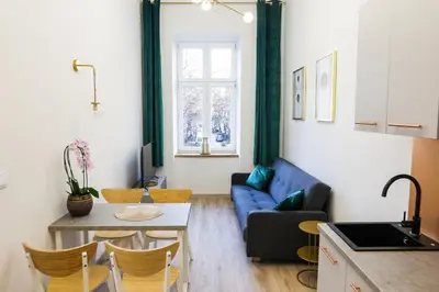 a living room with a blue couch and a table at CracWoW Saint Sebastian Apartments in Kraków